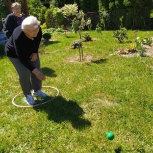 seniorka Dziennego Domu Pomocy w Jaśle rzuca piłeczką do celu biorąc udział w zabawie