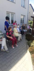 seniorzy Dziennego Domu Pomocy oraz opiekunowie biorą udział we wspólnej zabawie na świeżym powietrzu
