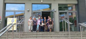 seniorzy oraz pracownicy Dziennego Domu Pomocy dla Osób Starszych w Jaśle stoją przy wejściu do Jasielskiego Domu Kultury
